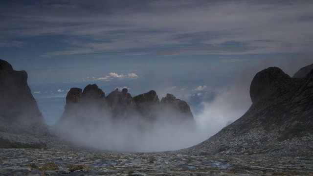 在婆罗洲基纳巴卢山的岩石山峰上，流逝的云滚滚而过视频素材