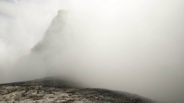 在婆罗洲基纳巴卢山，时断时落的云笼罩着岩石山峰视频素材