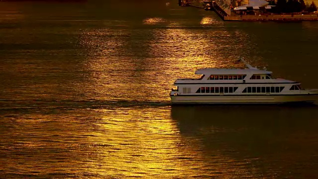 渡船沿着哈德逊河行驶，橙色的夕阳倒映在水面上。视频素材