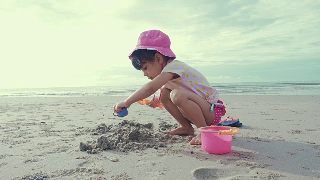 可爱的女孩在沙滩上玩沙子和快乐视频素材画面2