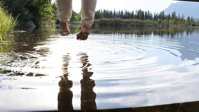 女人的双腿悬在山湖上方的桥上视频素材