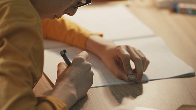 男孩坐在桌子旁做作业视频素材画面1