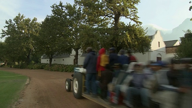 南非，西开普省，Franschhoek，人们开着拖拉机拖车穿过Boschendal Estate村视频下载