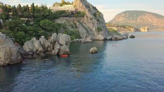 无人机飞行拍摄的邮轮旅游双体船通过海洋岩石海岸视频素材