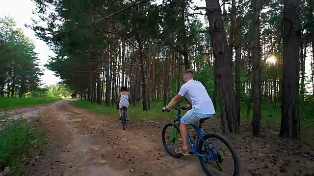 年轻快乐的夫妇在夏天的田野小径上骑车视频素材