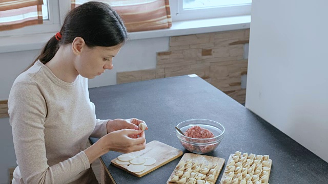 女人用碎肉包饺子。侧视图。视频素材