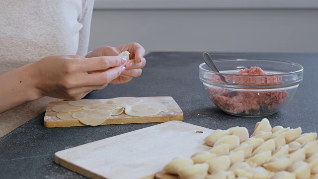 女人用碎肉包饺子，特写的手。侧视图。视频素材