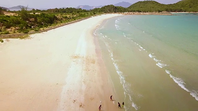 鸟瞰图，人们在天堂海滩游泳。无人机观看蓝色的大海和沙滩。从上面看，无人机飞过海洋海岸视频素材