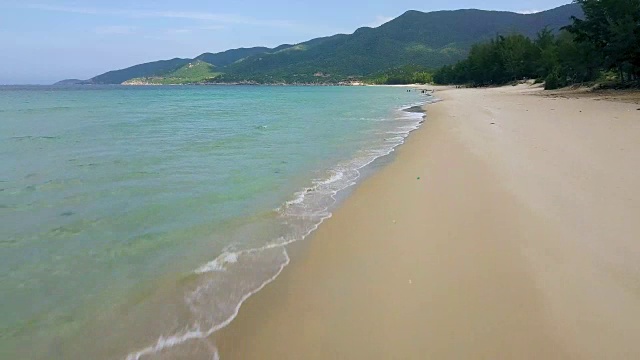 海岸上的沙滩和绿色的山地景观从无人机上方。空中景观海洋海岸和绿色山丘。度假海滩上的绿松石海水视频素材