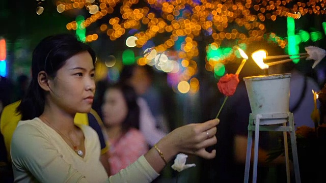 年轻的亚洲妇女为宗教仪式点燃蜡烛视频素材