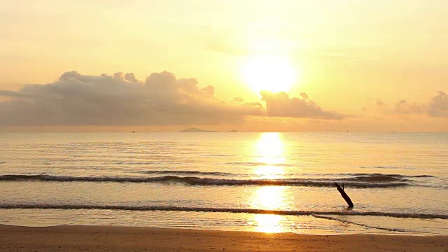 夕阳在黄昏时分与天空的黄色和橙色的海上慢慢波浪在热带海滩。视频素材