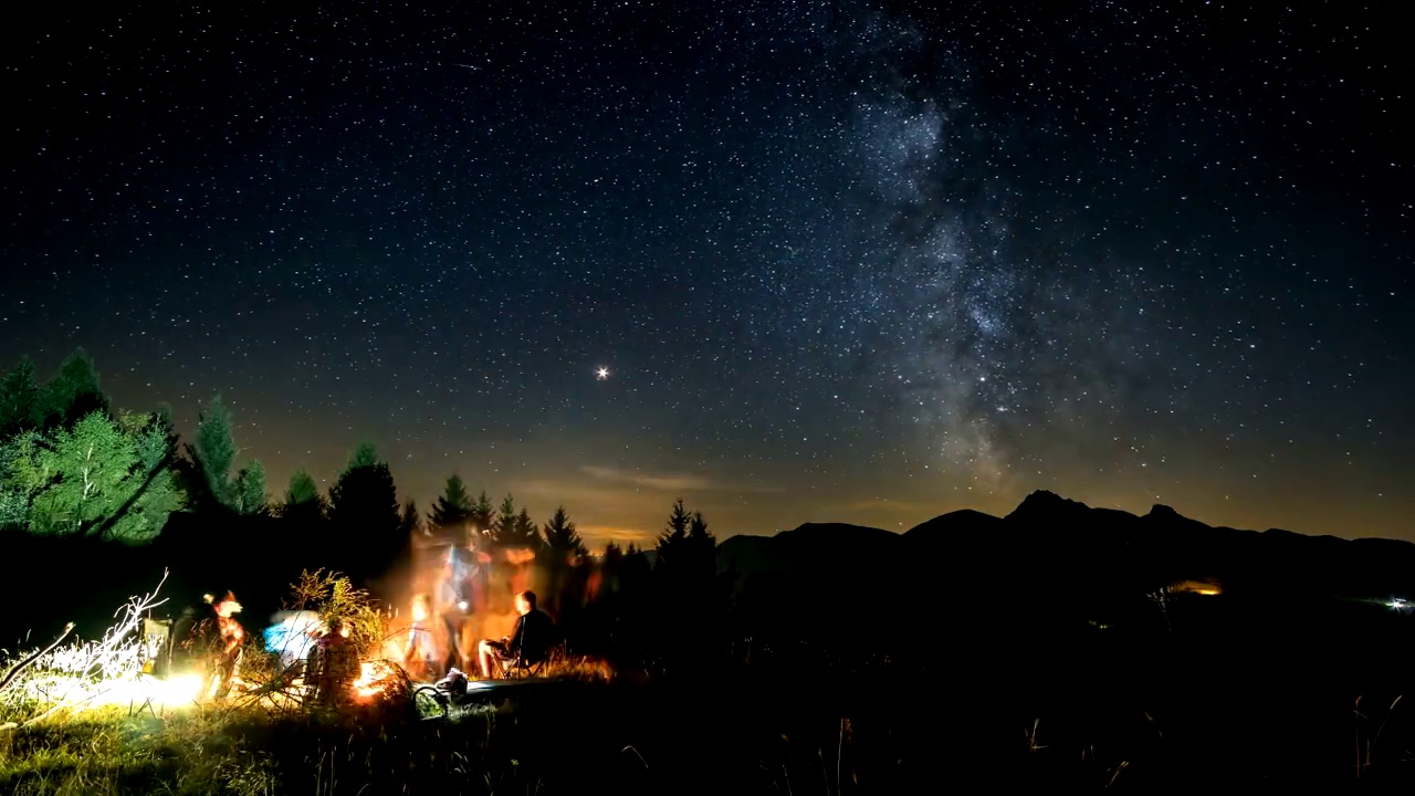 朋友们围坐在篝火旁，在星河星河的夜晚，时光流逝视频素材