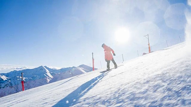 滑雪者在滑雪道上滑行，一边转弯一边喷雪，背景是群山视频素材