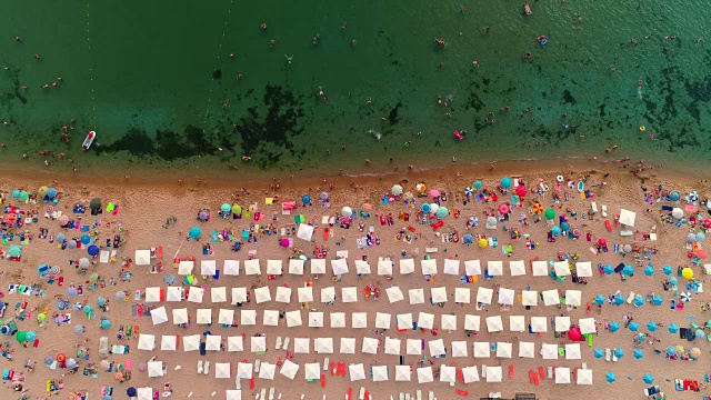 鸟瞰图的海滩。雨伞、沙滩、太阳椅和海浪视频素材