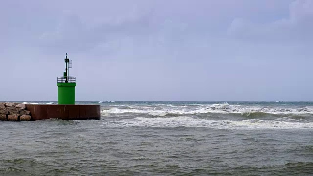 海浪拍打着港口入口的绿色灯塔塔。视频素材