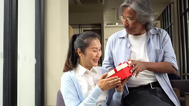 一对中年妇女和老年男子在她的特殊日子，如生日或结婚纪念日给她惊喜的礼物。庆祝及节日概念视频素材