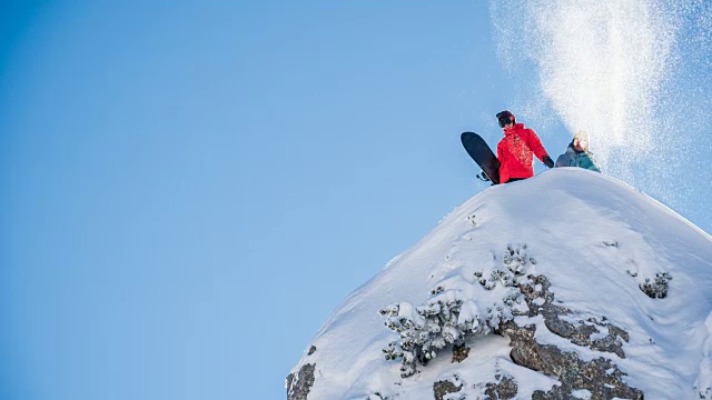 在一个阳光明媚的冬日，滑雪者站在雪山顶上视频素材