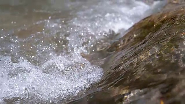 慢镜头，宏:清澈的河水流过棕色的石头。视频素材