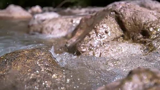 慢动作:闪光的河水溅过岩石的电影镜头。视频素材