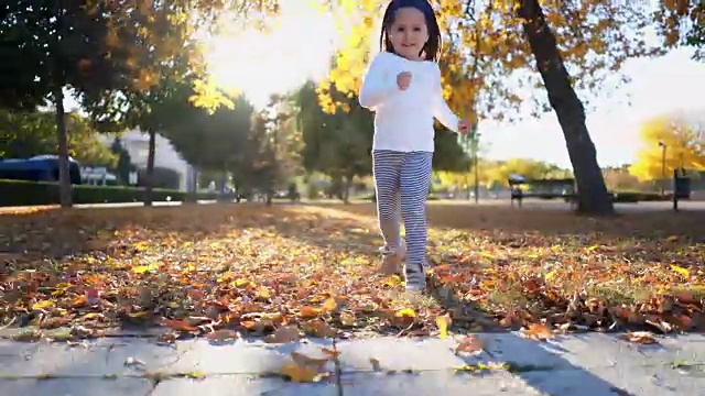 快乐和微笑的幼童在落叶中奔跑视频素材