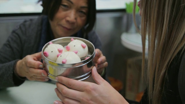 在香港一家餐馆里，女游客们正在享用可爱的猪形点心视频素材