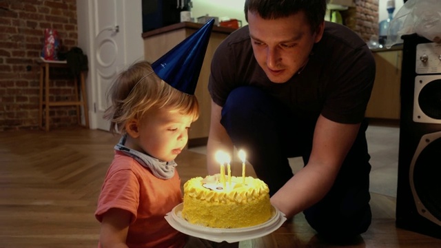 孩子在庆祝他的生日，吹蛋糕上的蜡烛视频素材画面3