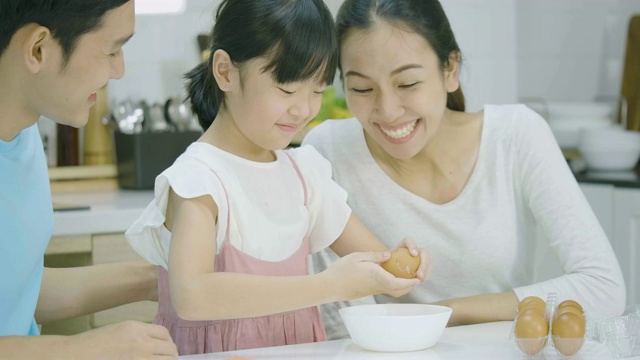 微笑的亚洲父亲，母亲和女儿喜欢在厨房一起准备健康的晚餐。母亲教女儿做饭。视频素材