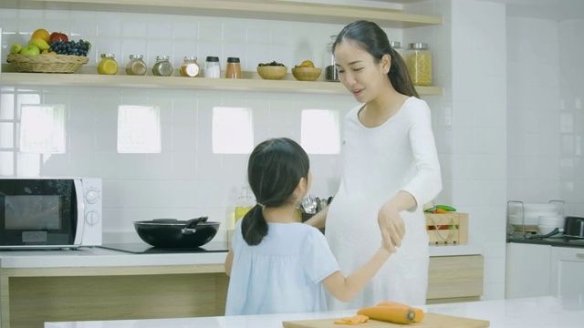 孕妇和她的女儿在家做饭和跳舞。家庭、食物、家庭、人的理念。视频素材