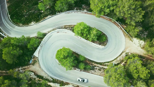 鸟瞰图视频的两个车道蜿蜒的道路在森林与一个自行车和一辆汽车视频下载