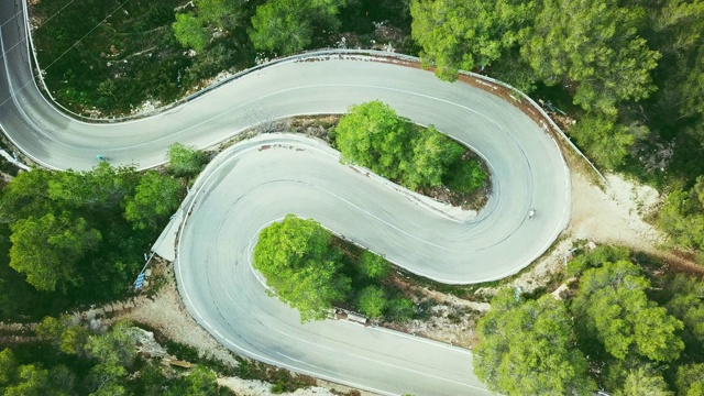 鸟瞰图视频的两车道蜿蜒的道路在森林与自行车和汽车视频下载