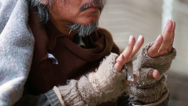 无家可归的老年人在街上用指甲钳剪指甲。视频素材画面1