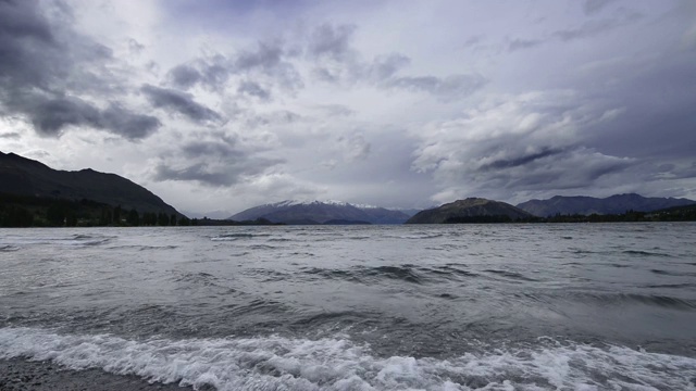 瓦纳卡湖的背景是白雪皑皑的山脉和戏剧性的云天空。瓦纳卡，瓦纳卡湖，奥塔哥地区，南岛，新西兰，大洋洲。视频素材