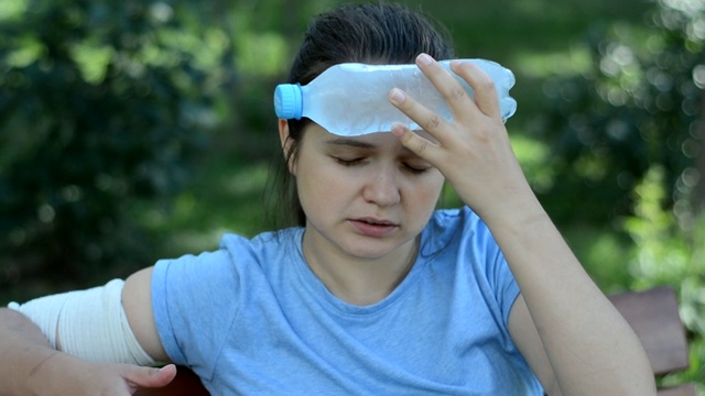 用一瓶冰水使这个女孩感到凉爽。视频素材画面1