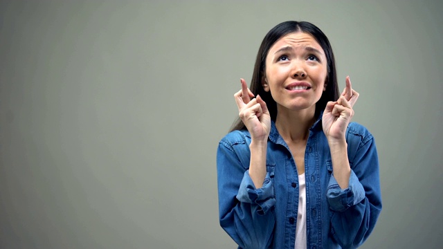 年轻女子交叉手指许愿，希望梦想成真视频素材