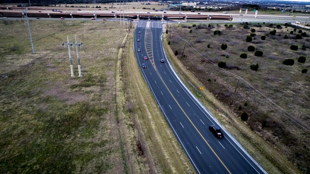 汽车在黑色的道路上经过，道路两旁是开阔的土地视频素材