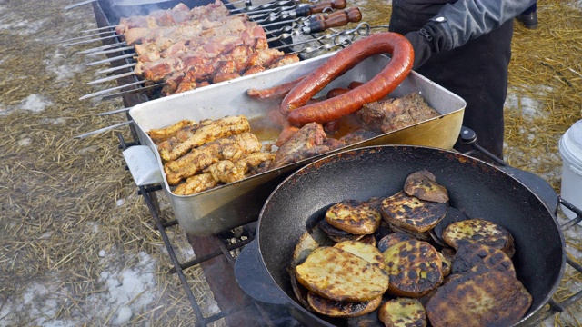 一个男人准备猪肉在烧烤架上煎土豆烤视频素材