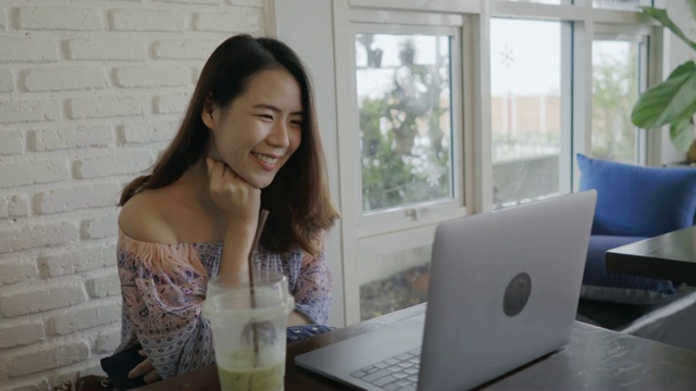 快乐微笑的女人看视频在咖啡厅使用笔记本电脑在放松的时间视频下载