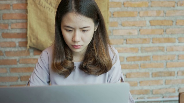 美丽的亚洲年轻女子在咖啡馆用笔记本电脑工作，关门视频素材