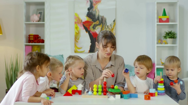 幼儿园的女老师和孩子们在餐桌上玩耍视频素材