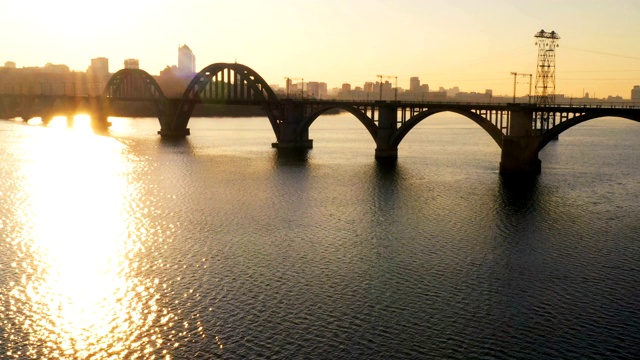 横跨河流的铁路桥和城市天际线的日落鸟瞰图，第聂伯，乌克兰视频素材