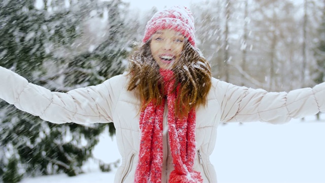 快乐的年轻女子扔雪在冬天的森林视频素材