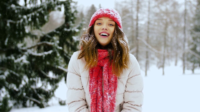 快乐的年轻女子扔雪在冬天的森林视频素材