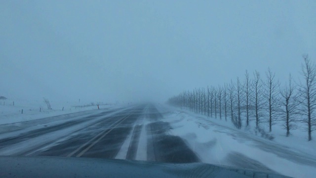 在冰岛乡村的道路上开车时，一场伴有强风的暴风雪在日出时袭来视频素材