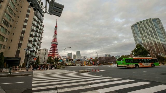 过马路的人群中有红绿灯和汽车，后面左边是东京塔——日本的东京视频素材