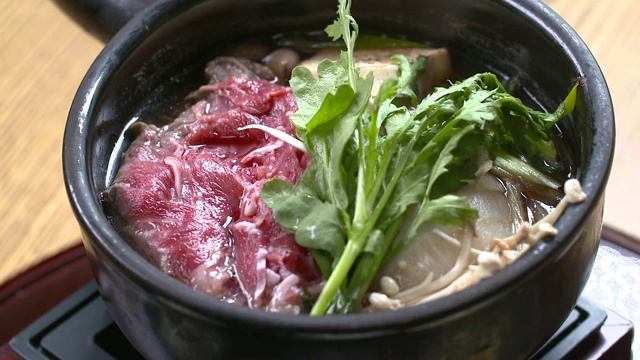 Sukiyaki(日式料理，以日本火锅的方式烹饪)被放在桌子上的景象视频素材