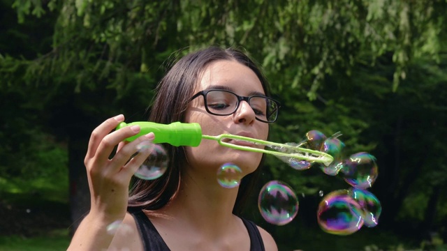 一个十几岁的女孩在夏天吹肥皂泡视频素材