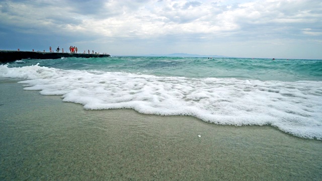 自然背景，海浪拍打海滩的沙子与码头的背景视频素材