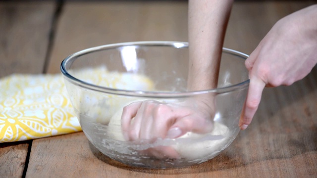 年轻女子在厨房里揉面团，特写视频素材