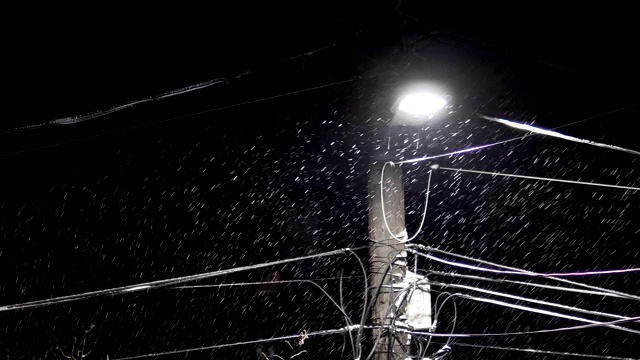 夜雪下城下街灯。街道柱子有密实的电线安装视频素材