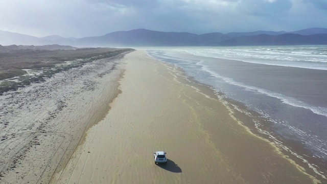 鸟瞰4k汽车在美丽的海滩上行驶。爱尔兰Inch海滩上的越野车视频素材